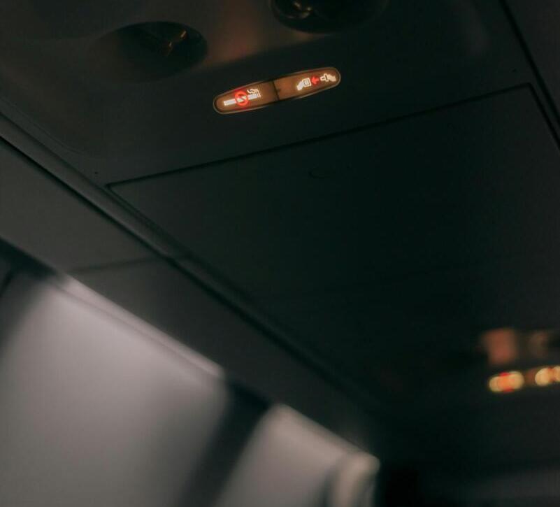 Close-up of an airplane cabin interior showing illuminated fasten seat belt sign.