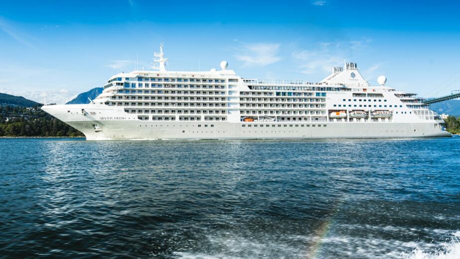 A large white cruise ship sails on a blue ocean.