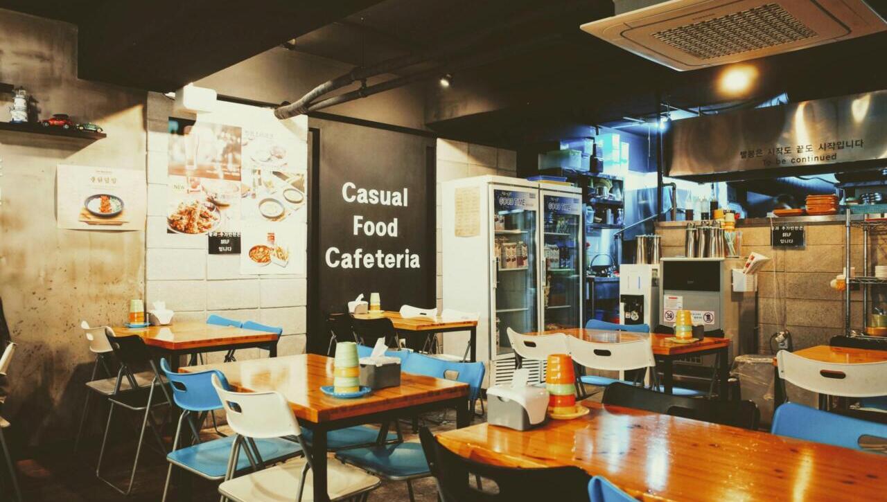 A cozy casual cafeteria interior with tables and chairs, located in Busan, South Korea.
