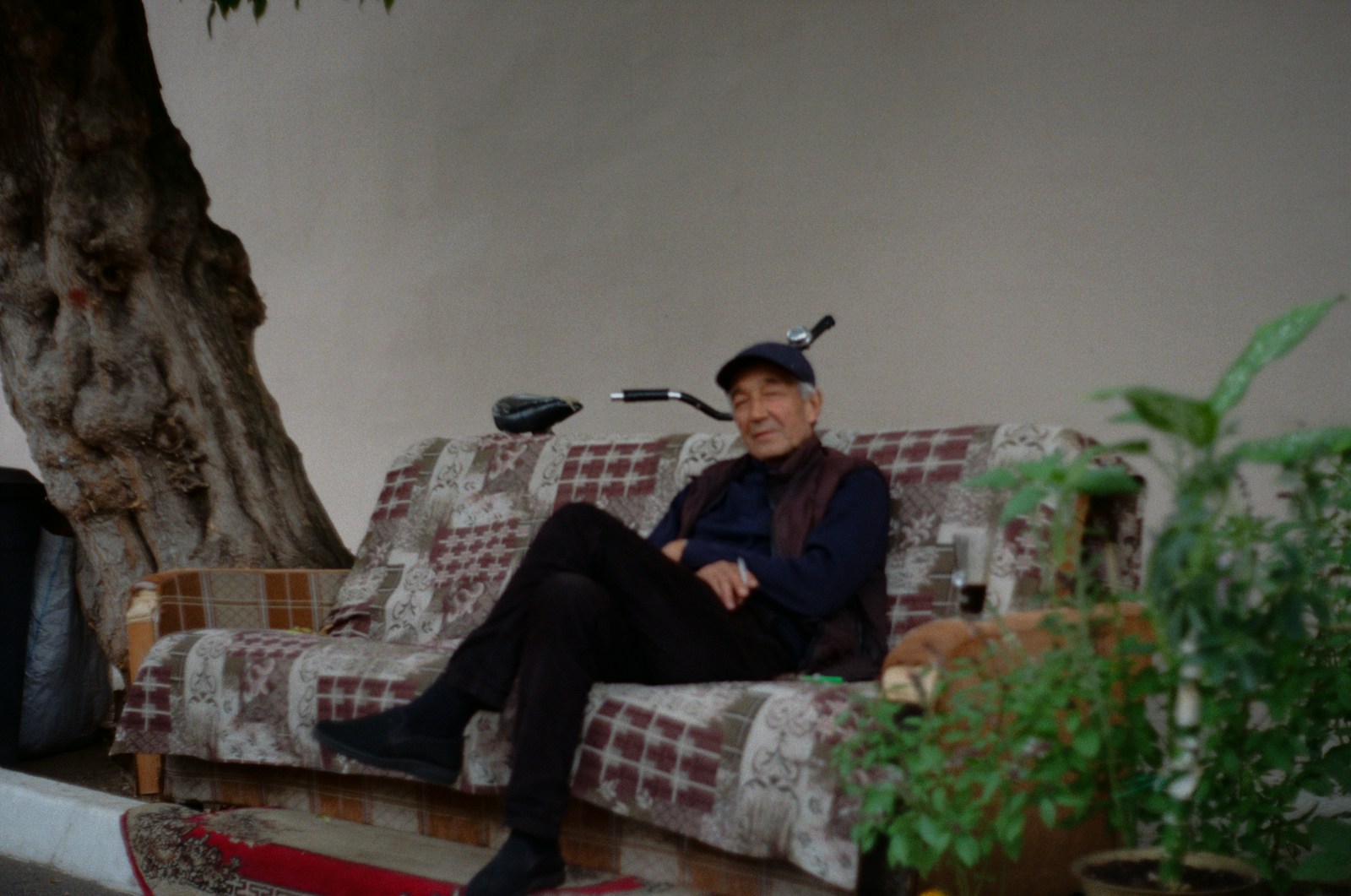 Elderly man sitting on a couch outdoors