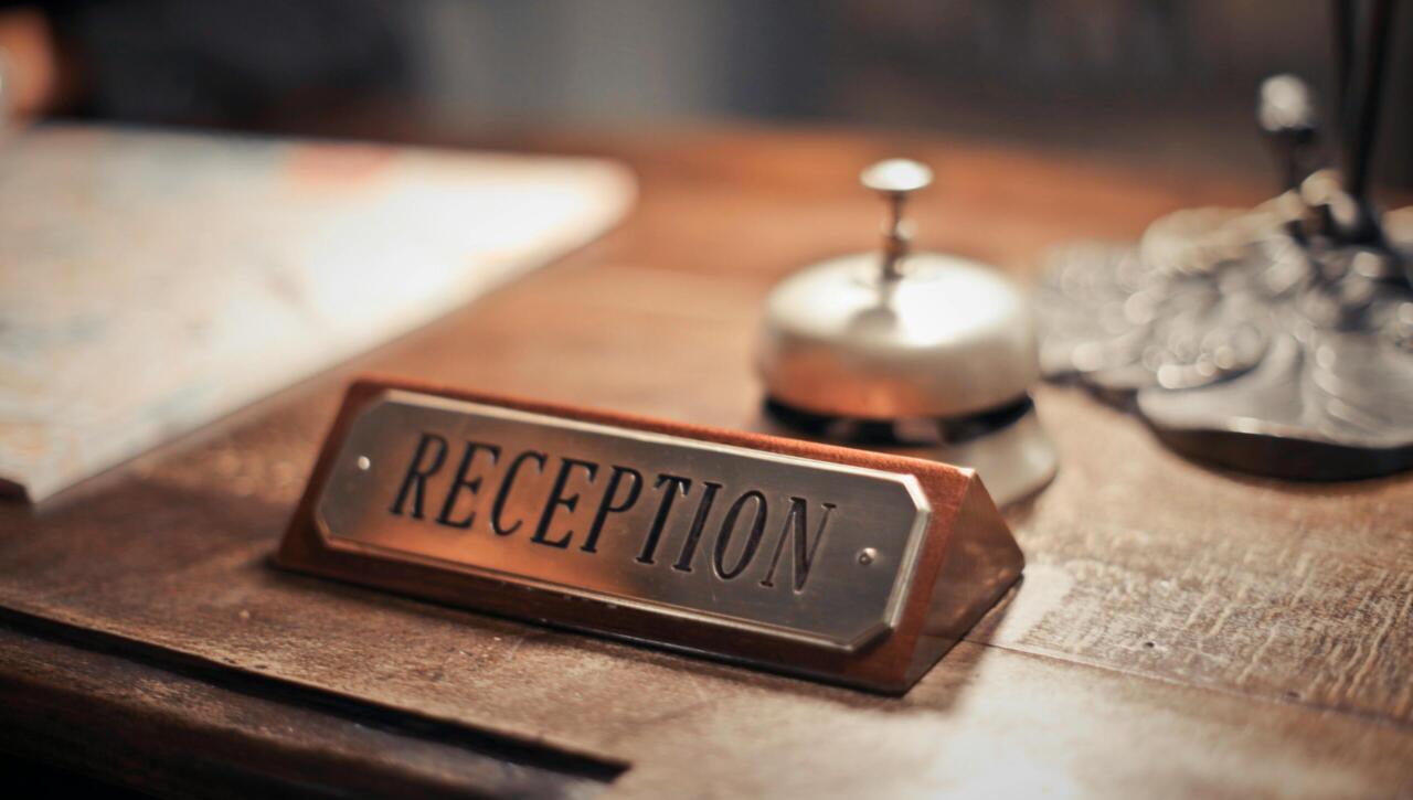 Close-up of a hotel reception desk showcasing a service bell and signage, emphasizing hospitality.