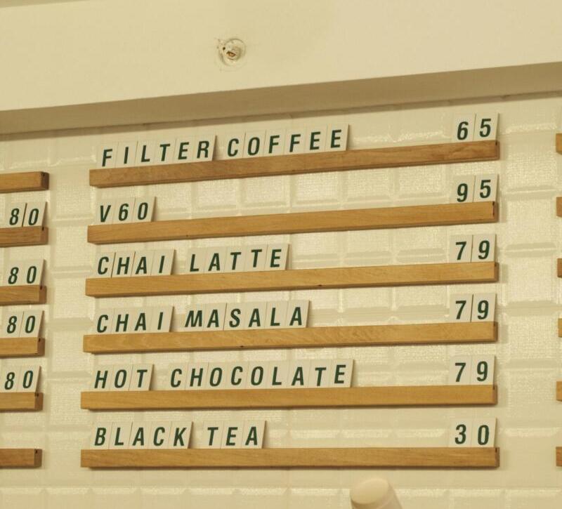 Warm café interior with menu board displaying coffee and tea options and prices.