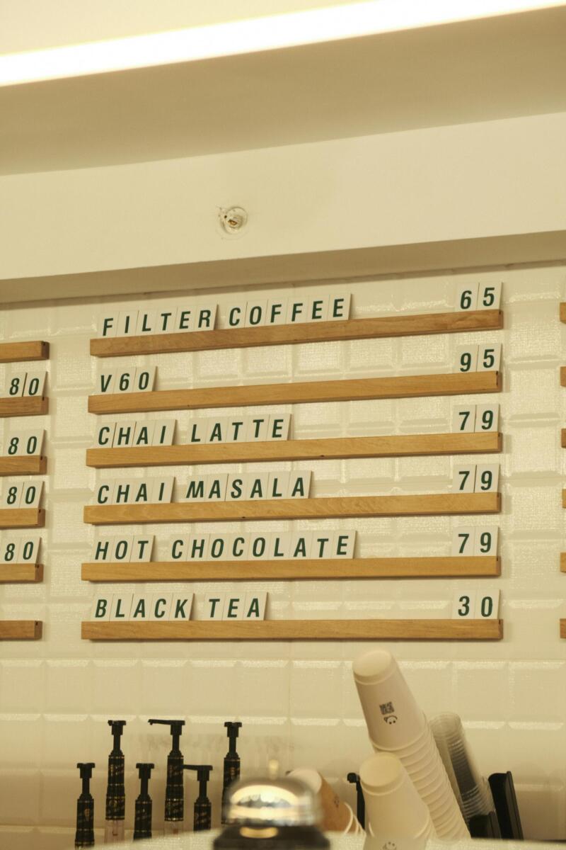 Warm café interior with menu board displaying coffee and tea options and prices.