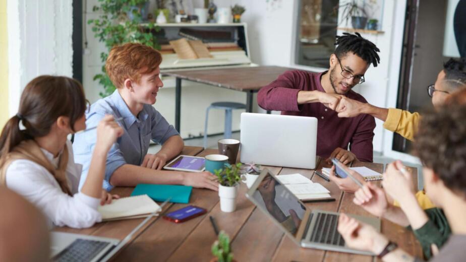 A diverse group of young professionals brainstorming around a table in a modern office environment.