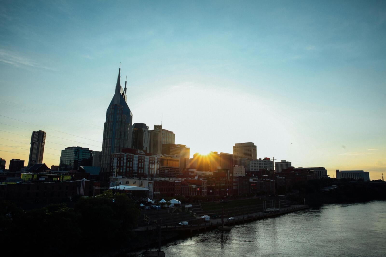 A stunning view of Nashville's skyline at sunset, featuring a calm waterfront reflection.
