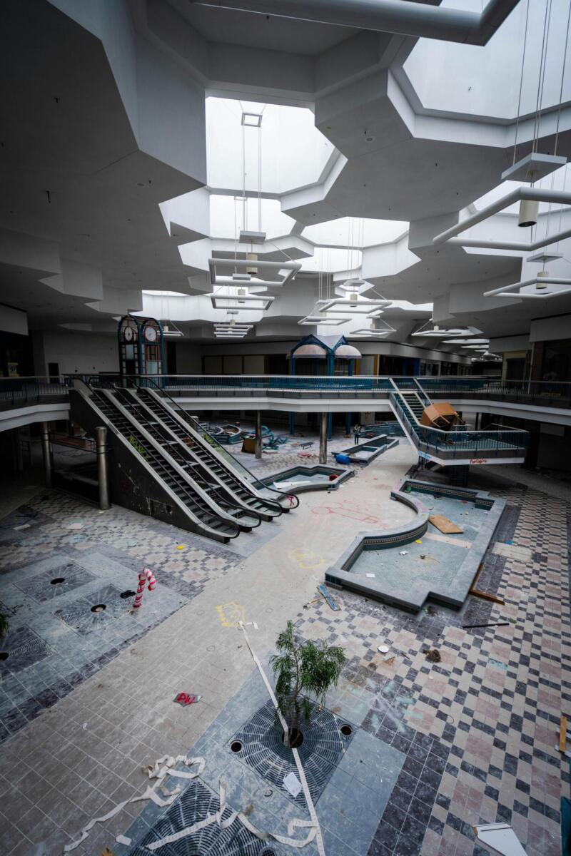 Eerie view of an abandoned mall, highlighting skylights and deserted escalators.