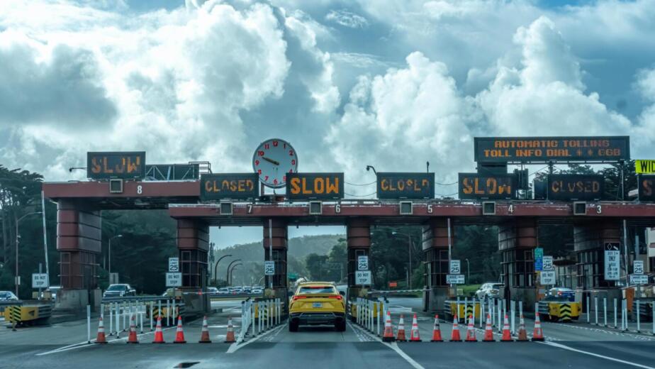View of vehicles approaching the toll plaza at Golden Gate Bridge in San Francisco under a cloudy sky.