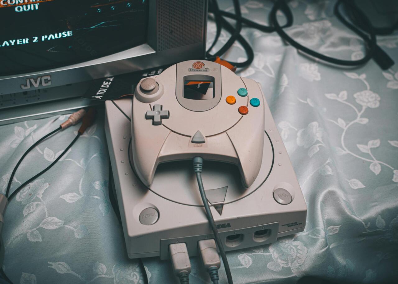 Close-up of a Sega Dreamcast console with controller and CRT monitor in a retro gaming setup.