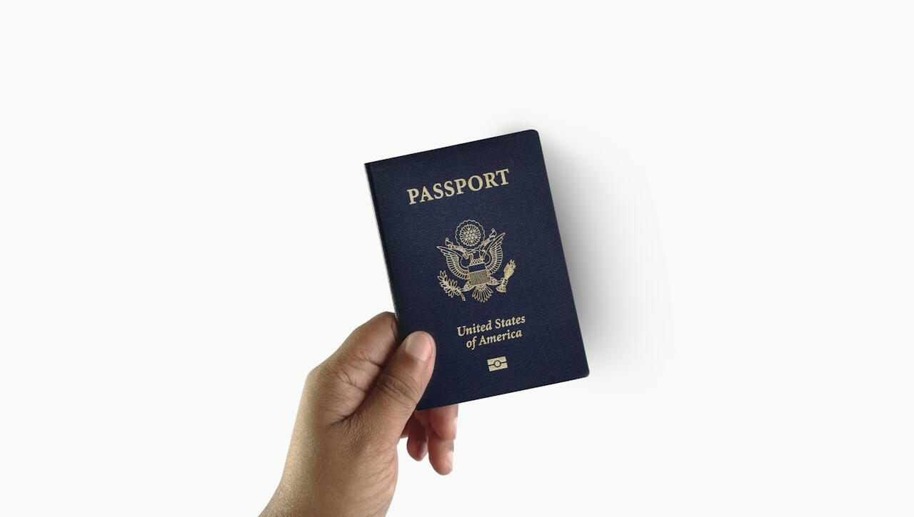 a hand holding a passport over a white background