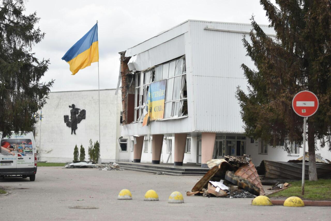 A damaged building with a Ukraine flag depicts the impact of war in an urban area.