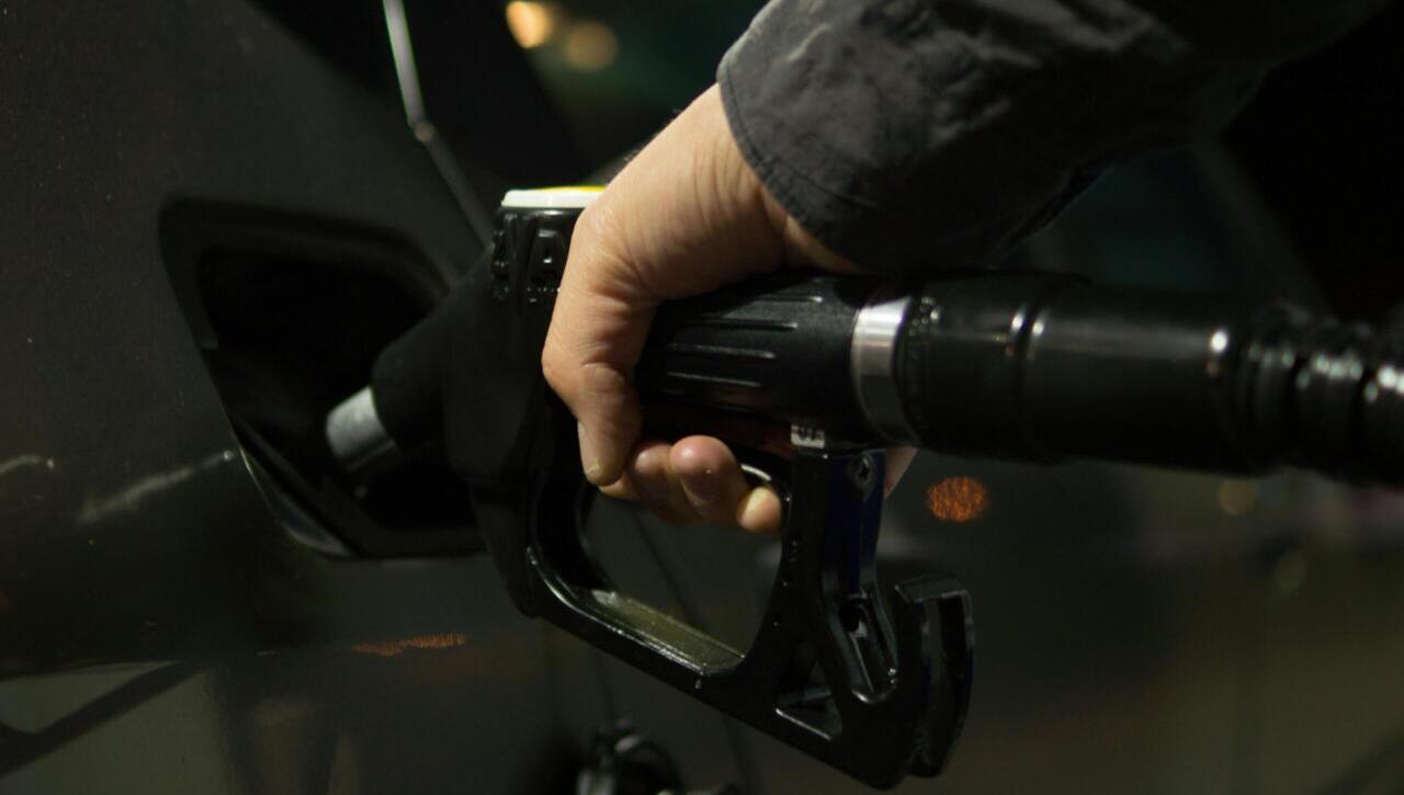 Close-up of a person refueling a car at a gas pump during night.